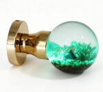 A resin door knob featuring a micro-landscape that emits a cyan glow, mounted on a round, gold-toned brass base.