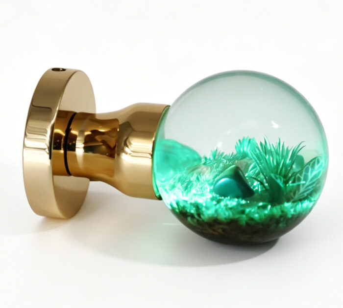 A resin door handle featuring a micro-landscape that emits a cyan glow. A resin door knob featuring a micro-landscape that emits a cyan glow, mounted on a round, gold-toned brass base.