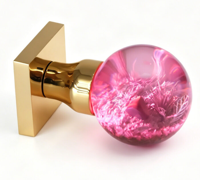 Micro-landscape resin door handle with pink illumination-1 Micro-landscape resin door knob emitting a pink glow, mounted on a square gold-tone brass base.