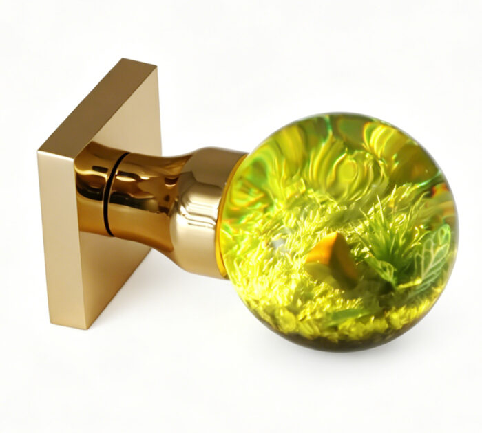 A resin door handle featuring a miniature landscape and emitting a warm yellow glow A resin door knob featuring a miniature landscape and emitting a warm yellow glow, mounted on a square gold-tone brass base.