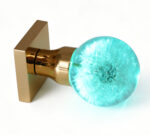 Dandelion Resin Door Knob Emitting a Cyan Glow, Mounted on a Square Gold Brass Base