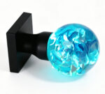 Handcrafted resin door knob featuring hydrangeas that emit a cyan glow, mounted on a square black brass base.